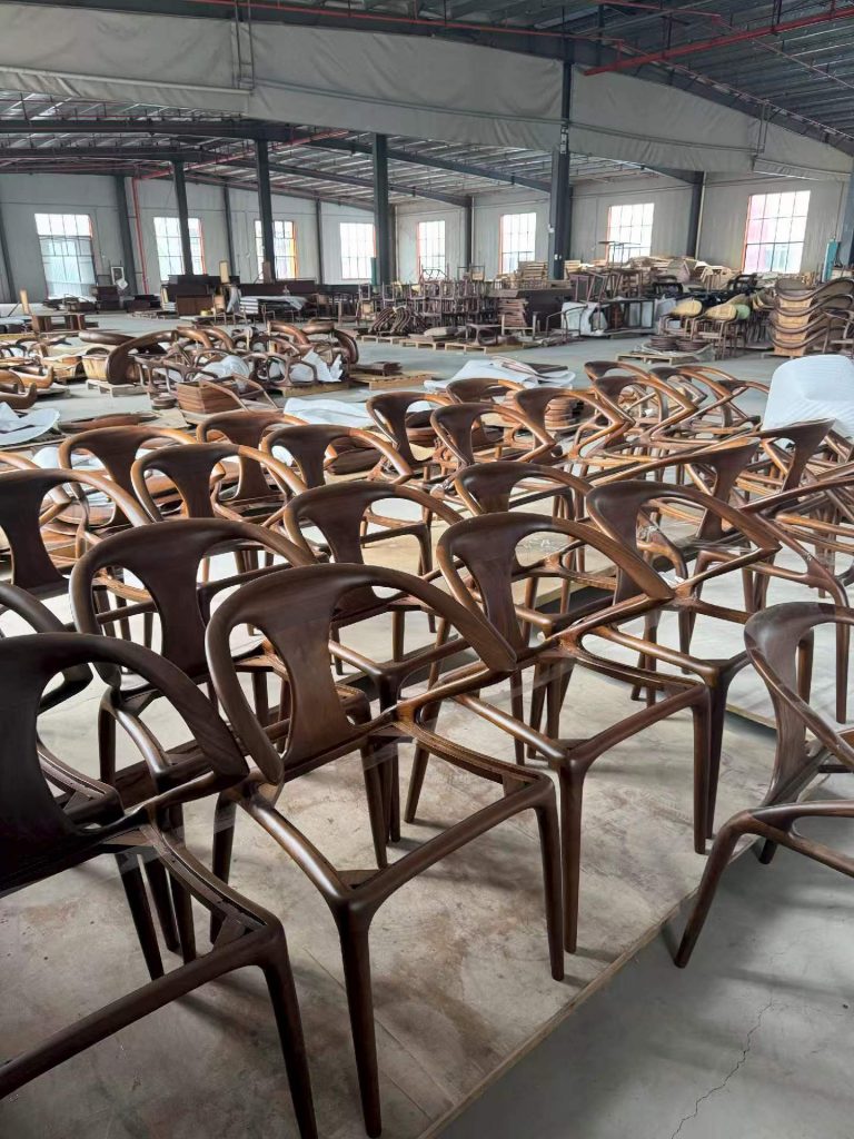 Batch of bespoke curved black walnut dining chairs on the factory floor, hand-finished and ready for upholstery