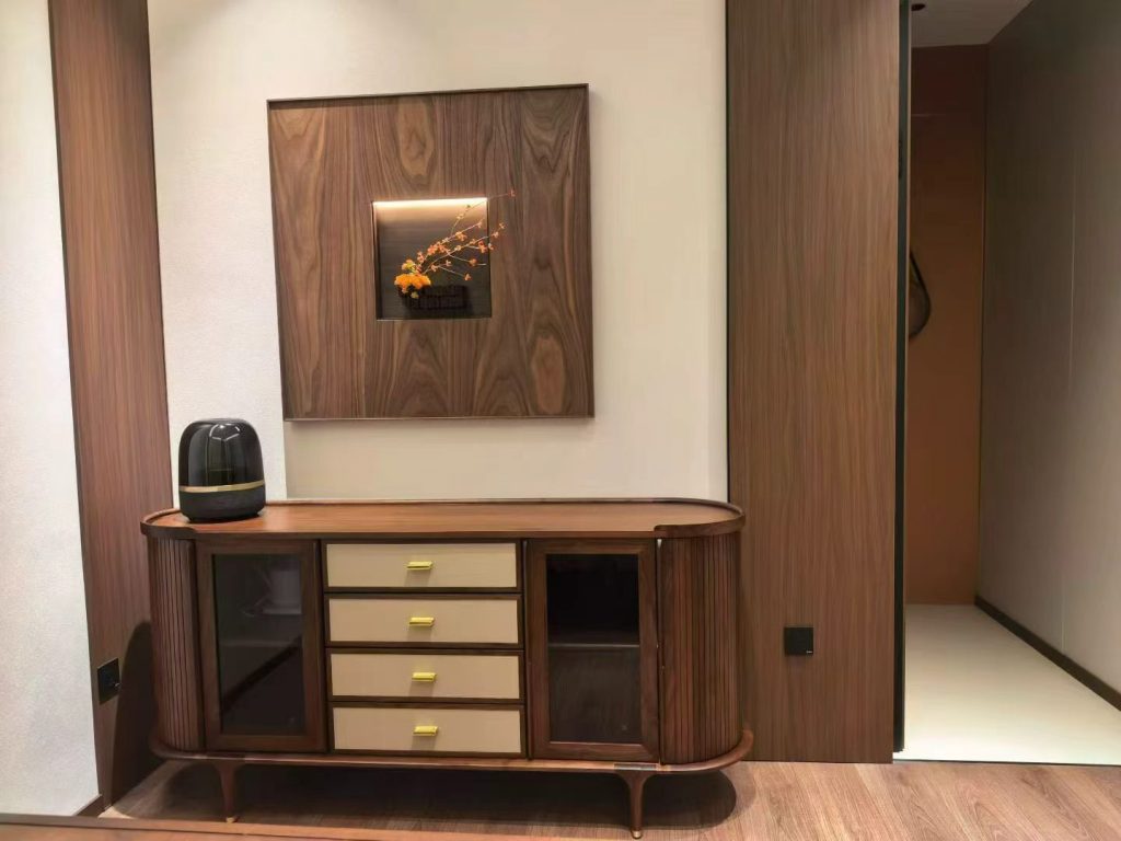 Curved fluted black walnut sideboard with leather-lined drawers and brass handles in the entryway
