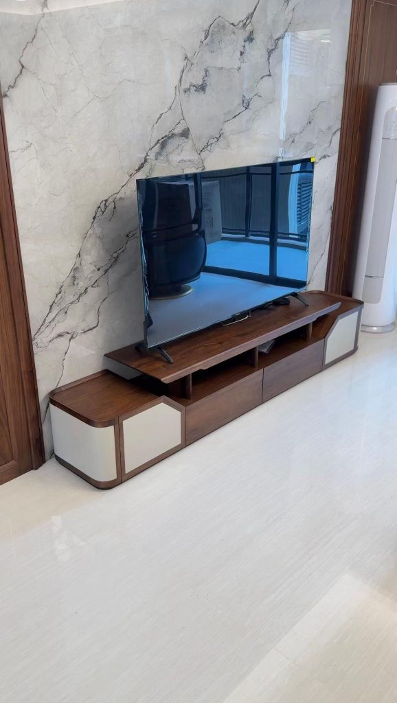 Low-profile walnut media console with cream panel doors against a marble feature wall in a villa
