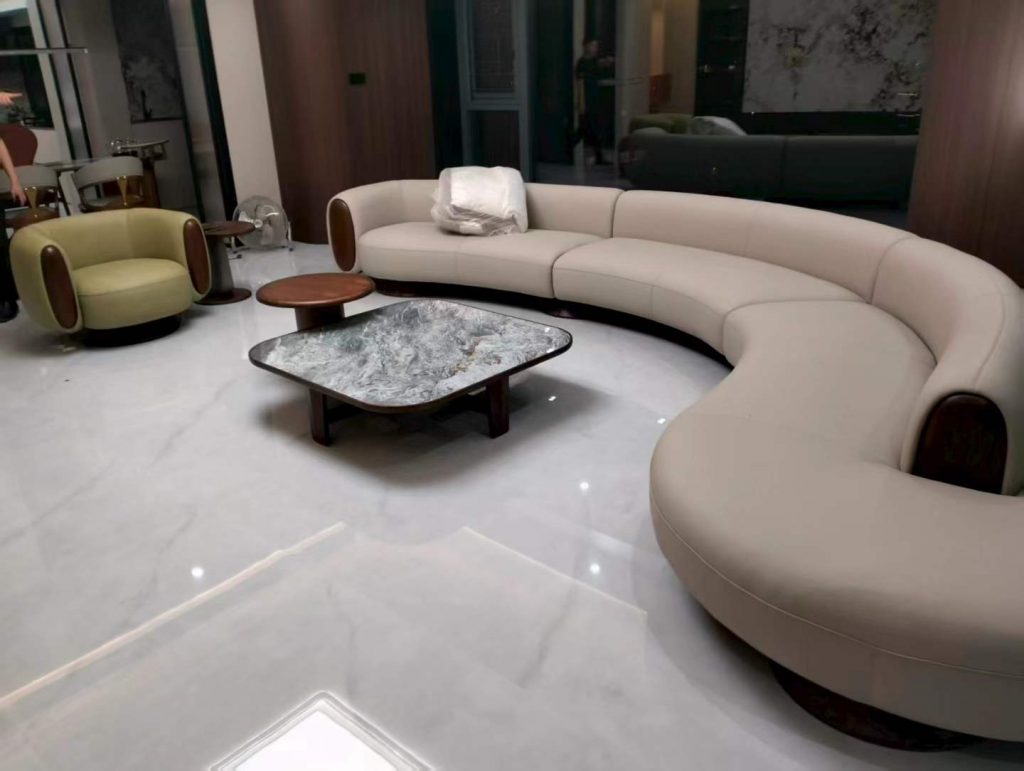Sculptural curved cream leather sofa with black walnut accents and stone-top coffee table in the lounge